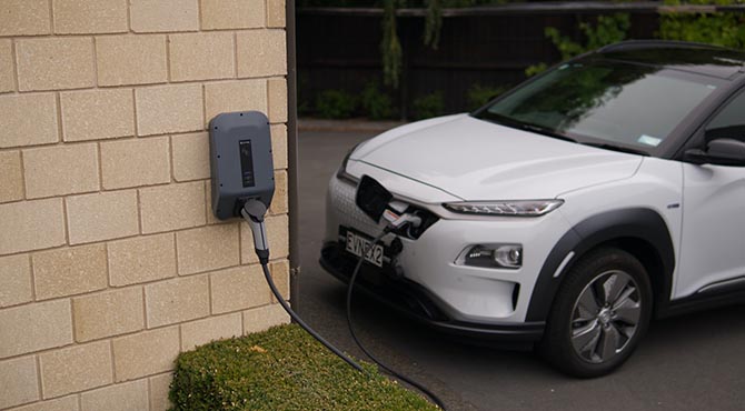 Beli automobil koji je priključen na električni punjač